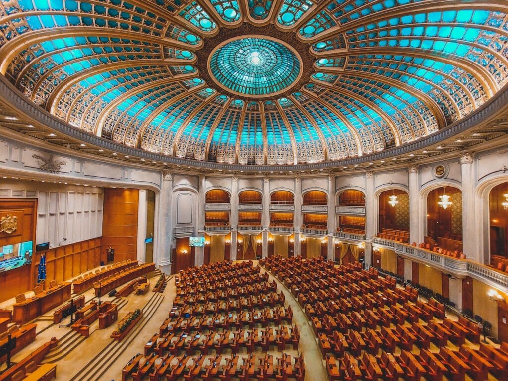 pexels-photo-15434151 Vibrant interior of a parliament hall with a grand dome and intricate architecture.